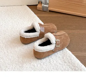 Detailansicht gemütlicher brauner gefütterter Birkenstock-Clogs für Kinder auf Teppich