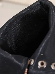 Close-up detail of black satin fabric texture and metal eyelets on fashion boots