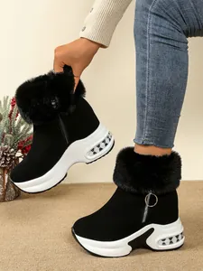 Close-up detail of black platform snow boots featuring plush faux fur collar and side zipper