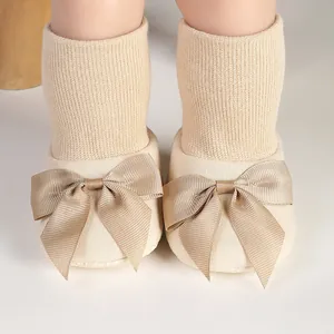 Gros plan de chaussures chaussettes pour bébé avec un grand nœud décoratif beige