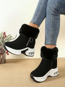 Close-up of black wedge snow boots with plush faux fur trim and thick white platform.