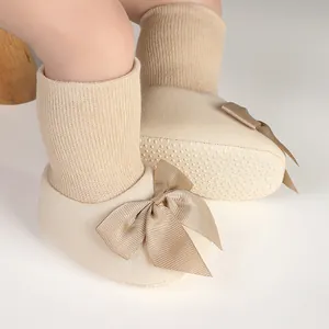 Gros plan de chaussettes de marche bébé beiges avec nœud en satin et semelle antidérapante