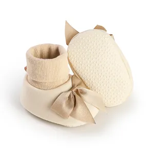 Vue détaillée de chaussures chaussettes bébé beiges avec nœud et semelle antidérapante