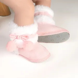 Detailed view of pink fuzzy baby shoes with soft non-slip sole and cute pom-poms