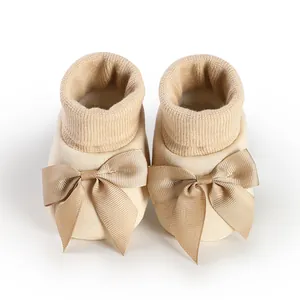 Vue détaillée de chaussons en tricot beige avec des nœuds décoratifs élégants