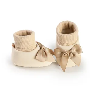 Vue détaillée de chaussures chaussettes beige bébé avec nœuds en satin et bords tricot