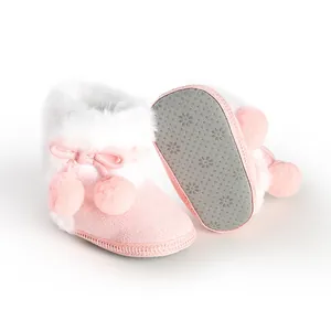 Close-up of cute pink soft-sole baby boots with white faux fur trim and soft pom-poms