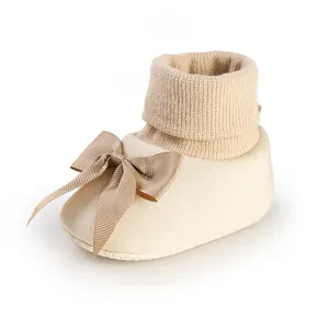 Gros plan d'une chaussette-chaussure pour bébé beige avec un nœud et un col en tricot