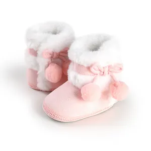 Close-up of pink baby princess boots with white faux fur and pom-pom ties