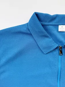 Gros plan sur le tissu gaufré bleu et la fermeture éclair de cette veste pour homme