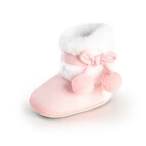Detailed view of pink baby princess boots with bow, pom-poms, and soft white fur trim