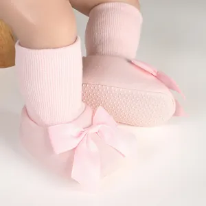 Vue détaillée des chaussons roses pour bébé avec nœud en soie et semelle antidérapante.