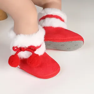 Gros plan sur les chaussons rouges pour bébé avec fourrure blanche et pompons décoratifs