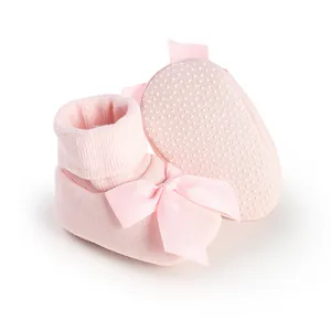 Vue détaillée de chaussons bébé roses avec nœud décoratif et semelles antidérapantes