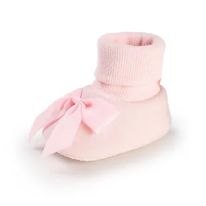 Détail rapproché d'un chausson rose pour bébé avec un grand nœud en ruban élégant