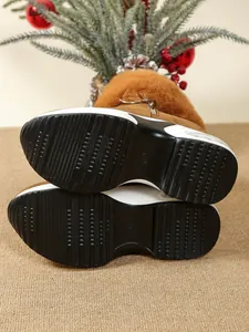 Detailed view of the non-slip thick wedge soles of brown fur-lined winter snow boots.