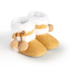 Detailed macro view of yellow soft-sole infant booties with white fluffy fur and pom-poms.