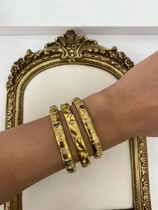 Close-up view of luxury gold stainless steel bangles featuring flower star and moon patterns
