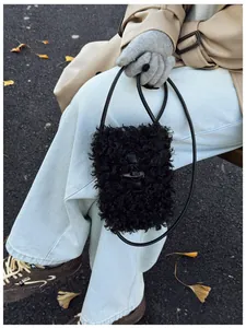 Macro view of a stylish retro fuzzy black plush crossbody bag with toggle closure
