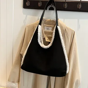 Elegante zwarte suède hobo tas met witte imitatie lamswollen bies en lederen schouderband