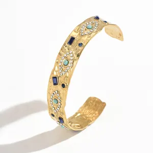 Detailed macro shot of vintage gold cuff bracelet featuring turquoise evil eye accents