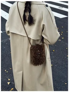 Detailed view of brown faux fur crossbody phone bag on a beige trench coat