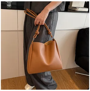 Large capacity tan faux leather tote bag with unique knotted handle details shown in use