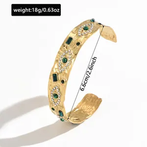 Detail view of a gold-plated stainless steel cuff bracelet with green gemstones
