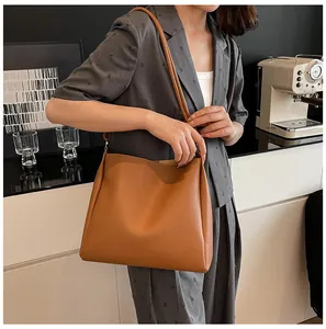 Detail of a brown faux leather large capacity tote bag shown on model's shoulder