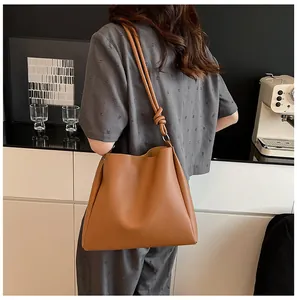 Large capacity tan tote bag carried by a model in a modern kitchen setting