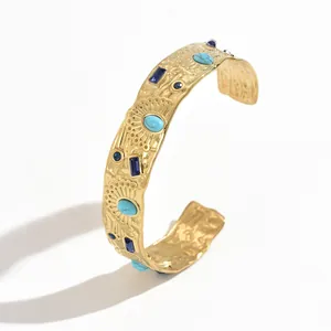 Close-up detail of a textured gold stainless steel C-shaped cuff with turquoise stones