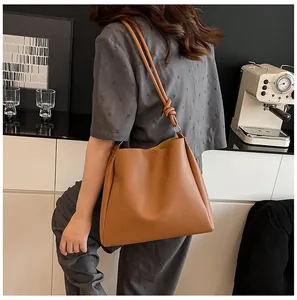 Stylish model wearing a large brown retro faux leather tote bag in a modern cafe setting