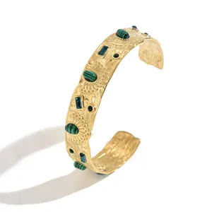 Detailed view of gold-plated cuff bracelet with green malachite and floral patterns