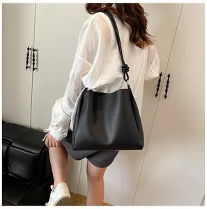 Stylish black large capacity shoulder bucket bag with knot detail worn by a model