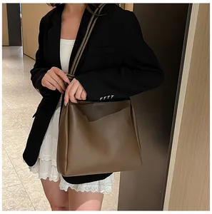 Model wearing a large brown retro leather tote bag in a professional indoor setting