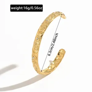 Detailed view of gold C-shape cuff bracelet with celestial sun moon engravings and size info.