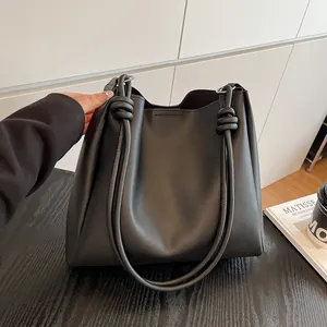 Stylish large black vintage tote bag featuring decorative knot shoulder straps on a desk