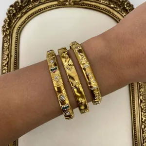 Set of three gold stainless steel bangles with sun, star, and moon patterns for women