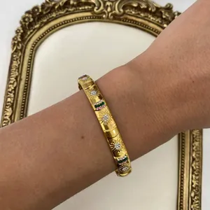 Elegant gold-colored sunburst bangle with colorful rhinestone accents for modern women.