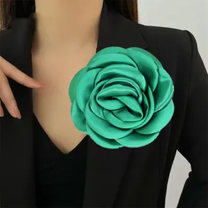 Grande spilla camelia a rosa verde da 12cm fatta a mano appuntata su un blazer nero.