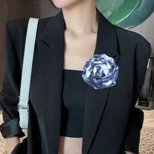 Primo piano di una spilla a forma di rosa in tessuto blu su un blazer nero