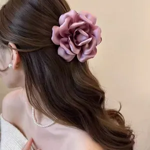Close-up detail of a large purple satin rose hair claw clip worn on a woman's brown hair.