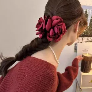 Detail view of a large burgundy satin flower hair claw clip styled on a braided hairstyle
