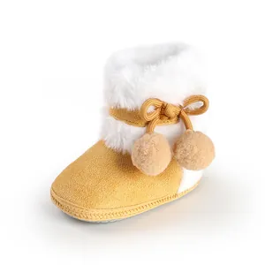 Detailed view of yellow infant bootie with white faux fur and decorative pom-poms