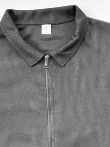 Gros plan de la texture en maille gaufrée grise et du zip argenté sur la veste col