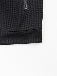 Détail macro d'une veste noire avec tissu gaufré et une poche zippée pratique.