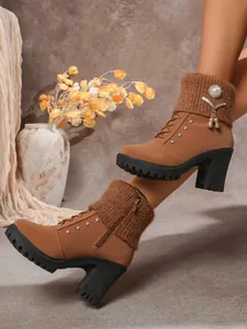 Detail view of brown high-heeled boots with knit cuffs, pearls, and sparkling rhinestones.