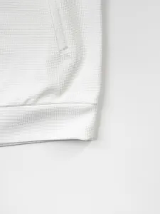 Gros plan du tissu gaufré blanc sur l'ourlet d'un cardigan zippé moderne pour homme