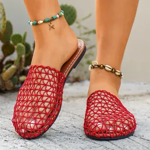 Eleganti ciabatte piatte rosse in rete traforata per donna in un ambiente di vacanza