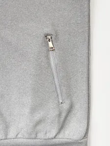 Gros plan sur la poche zippée oblique d'une veste en maille grise pour homme de haute qualité
